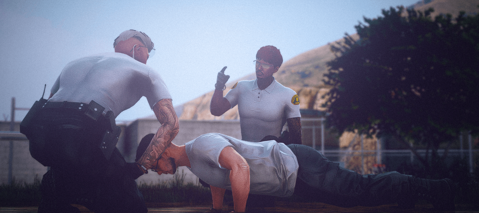 Dos ayudantes del sheriff supervisan a un detenido en las afueras de Blaine County bajo el sol.